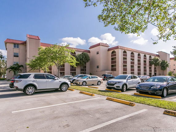 Outdoor parking area in front of a multi-story residential building.