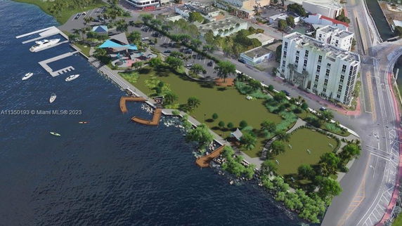 Aerial view of a waterfront area with a dock, buildings, and green space.