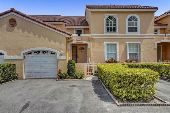 Front view of a two-story townhouse with a garage and arched windows.