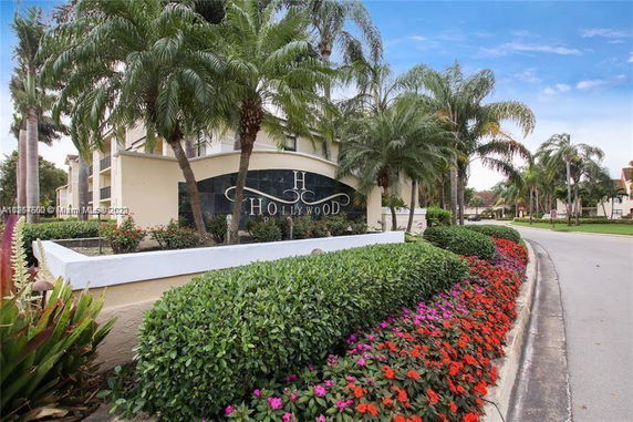 Front view of a building with a prominent sign reading 'Hollywood' surrounded by palm trees and flower beds.