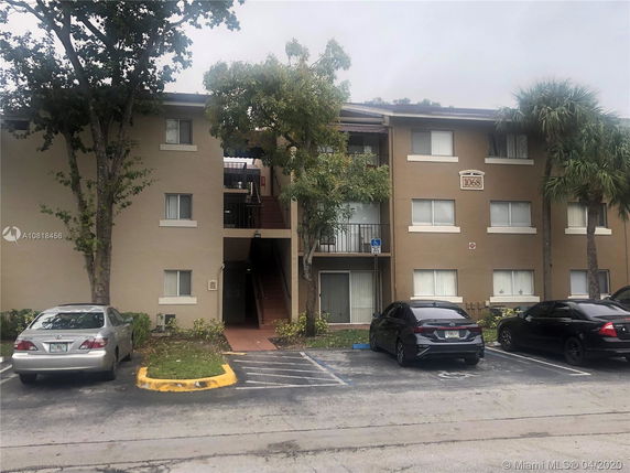 Front view of a three-story apartment building with parking spaces.