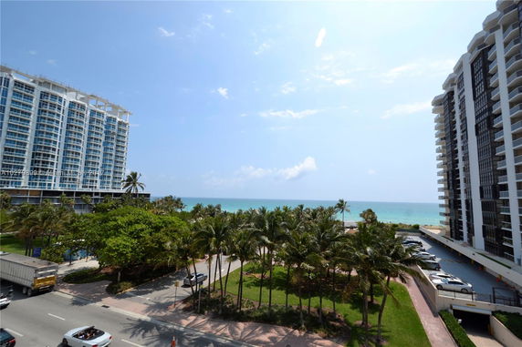 View of buildings with ocean and palm trees in the background.