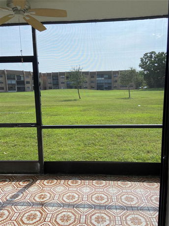 Exterior view of buildings and grassy area from a screened porch.