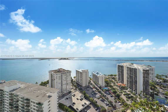 Panoramic view of coastal area with multiple high-rise buildings and a distant bridge over water.