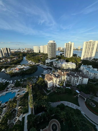 Panoramic view of multiple high-rise buildings near a waterway and green areas.