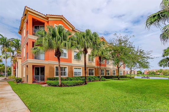 Front view of a multi-story building with palm trees and well-maintained landscaping.