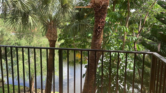 View from a balustrade showing lush greenery and a body of water in the background.