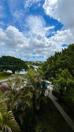 Scenic view of trees and a lake with a clear, cloudy sky.