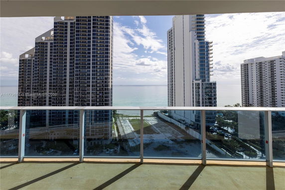 Panoramic view from a building balcony overlooking high-rise buildings and the ocean.