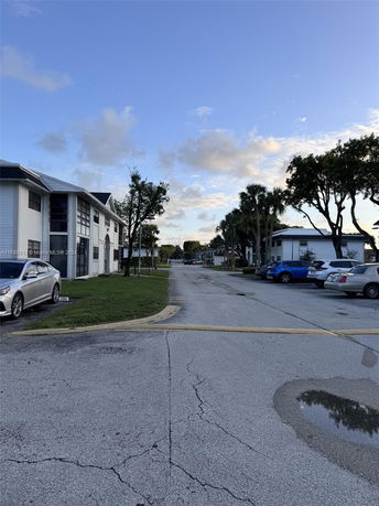 Outdoor parking area with cars parked beside a two-story residential building.