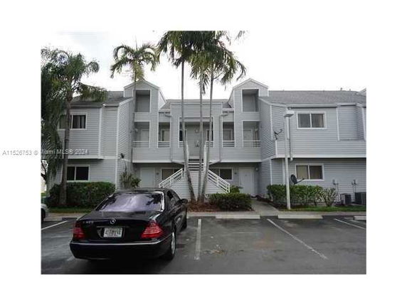 Front view of a multi-story residential building with a parking area in front.