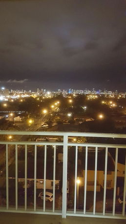 Night view from a balcony overlooking a cityscape with illuminated buildings.
