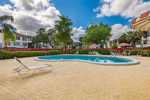 View of an outdoor swimming pool with surrounding lounge chairs and umbrellas.