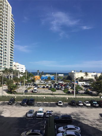 Wide angle view from building overlooking parking area and distant ocean.
