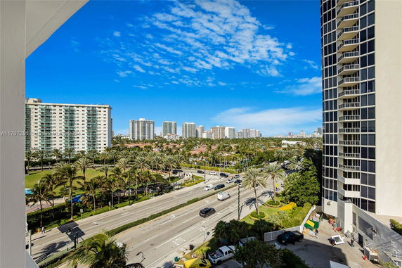 View of tall residential buildings and palm-lined roads in an urban area.