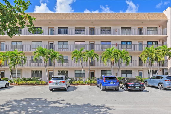 Front view of a multi-story building with balconies and parking area.