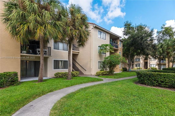 Front view of a three-story apartment building with balconies and a walkway.