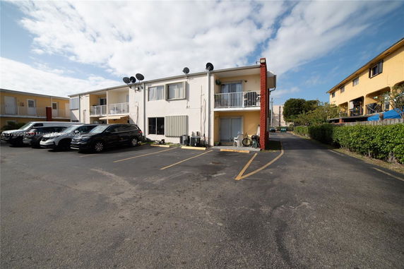 Parking area in front of a two-story residential building with balconies.