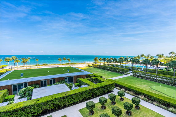 Panoramic view of a lush green lawn and a building with a rooftop near the ocean.