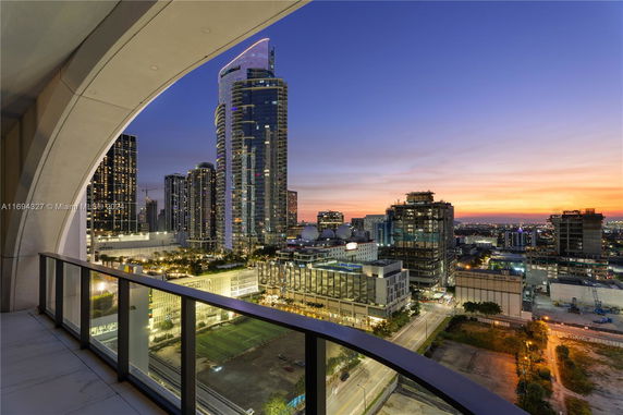 Panoramic view of a city skyline at sunset from a balcony.