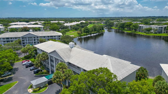 Aerial view of residential buildings near a body of water with surrounding greenery.
