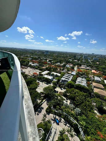 Panoramic view from a high-rise building showing cityscape and surrounding greenery.