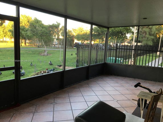 View from a screened-in porch overlooking a grassy area with trees and ducks.