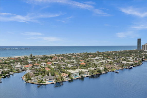 Panoramic view of a coastal neighborhood with houses, greenery, and the ocean in the background.