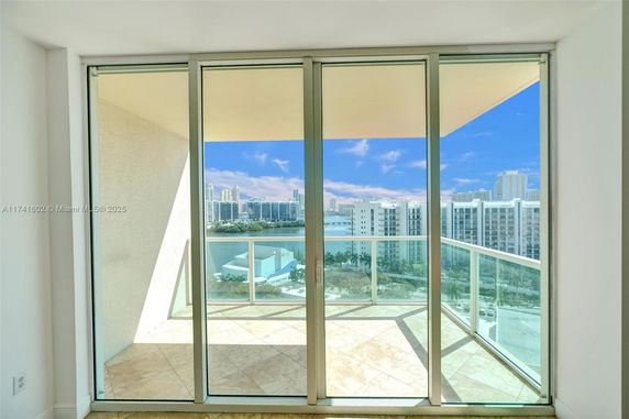 View of surrounding area with buildings seen from a balcony with glass railings.
