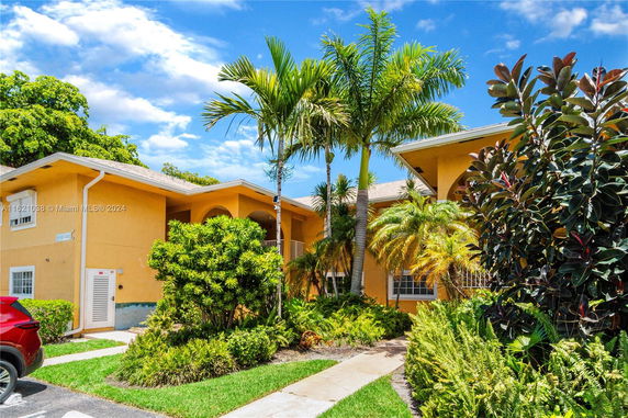 Front view of a two-story building with arched entryways and palm trees.