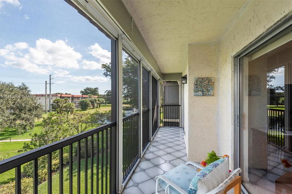 View from a screened balcony overlooking green areas and distant buildings.