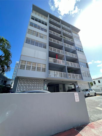 Front view of a multi-story residential building with balconies and large windows.