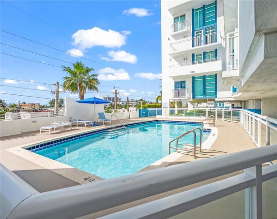 View of a multi-story building with a swimming pool on the ground level.