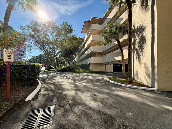 Front view of a multi-story building with staggered balconies and a driveway.