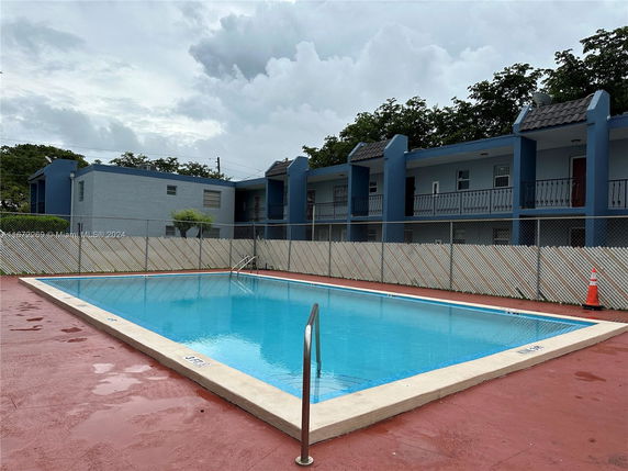 Outdoor swimming pool in front of a residential building with blue accents.