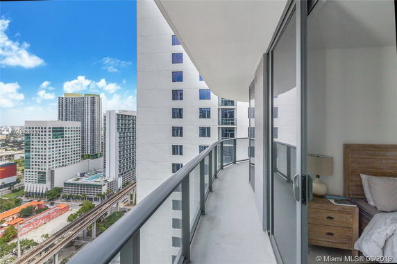 View from a high-rise balcony overlooking neighboring buildings in a cityscape.