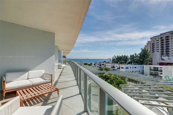 Panoramic view of a balcony overlooking the ocean and surrounding buildings.