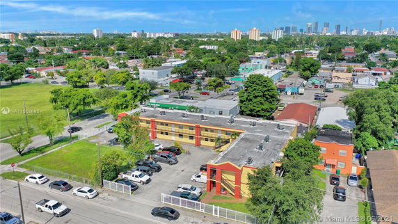 Panoramic view of a neighborhood with a multi-story building and nearby residential and commercial structures in the background.