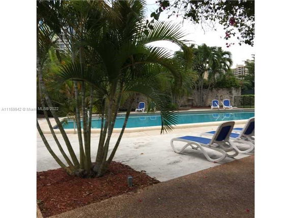 Outdoor swimming pool with lounge chairs and surrounding plants.