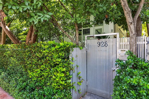 Front view of a house entrance with a metal gate and surrounding greenery.