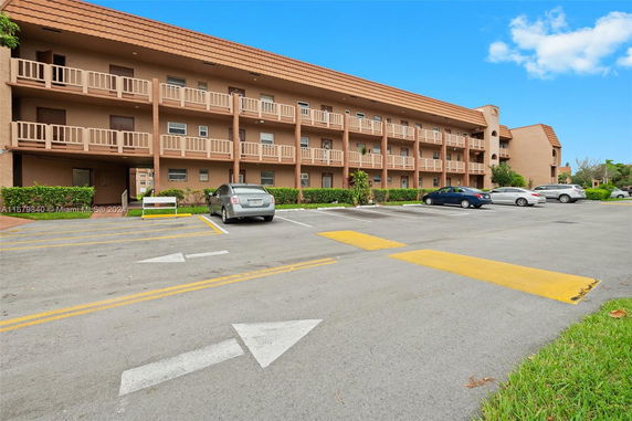 Parking area in front of a three-story residential building with balconies.