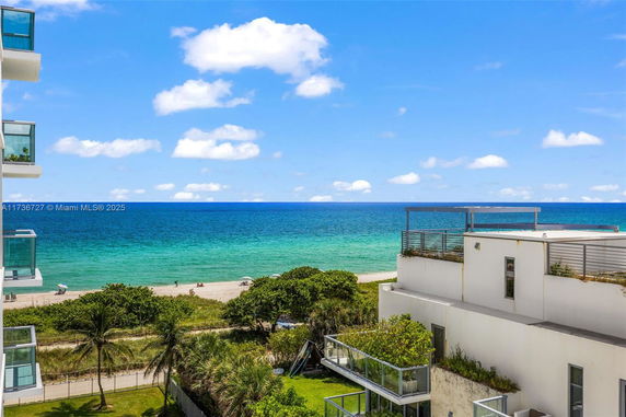 View of beach and ocean with white buildings in the foreground.