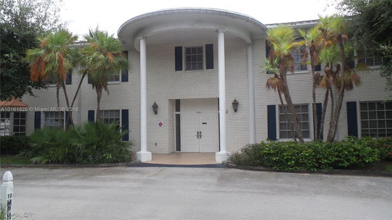 Front view of a two-story house with white brick exterior and large columns.