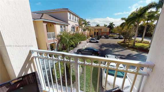 View from a balcony overlooking a parking area and neighboring buildings.