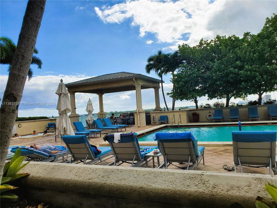 Outdoor swimming pool area with lounge chairs and a covered seating pavilion.