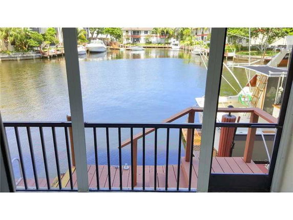 View from a covered balcony overlooking a waterfront area with boats and surrounding buildings.