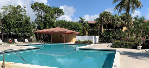Outdoor view of a swimming pool with surrounding trees and lounge chairs.