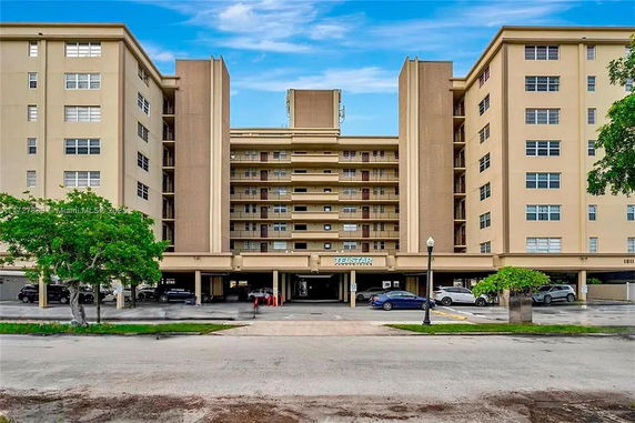 Front view of a multi-story residential building with parking area.