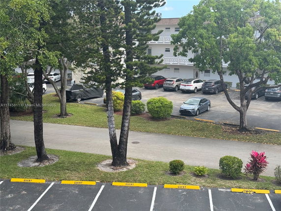Outdoor parking area with multiple cars near a residential building.