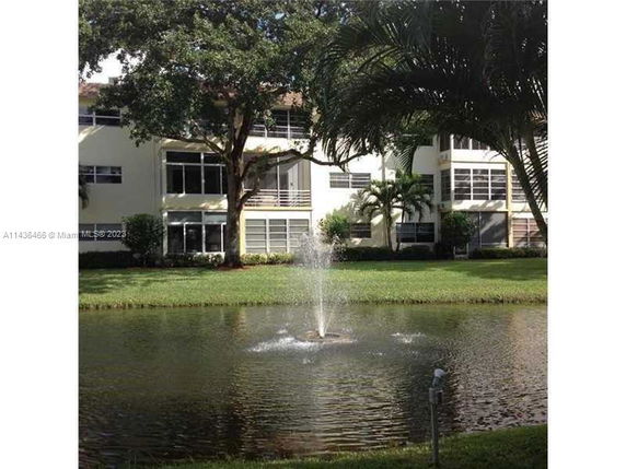 View of a multi-story building with a pond and fountain in the foreground.